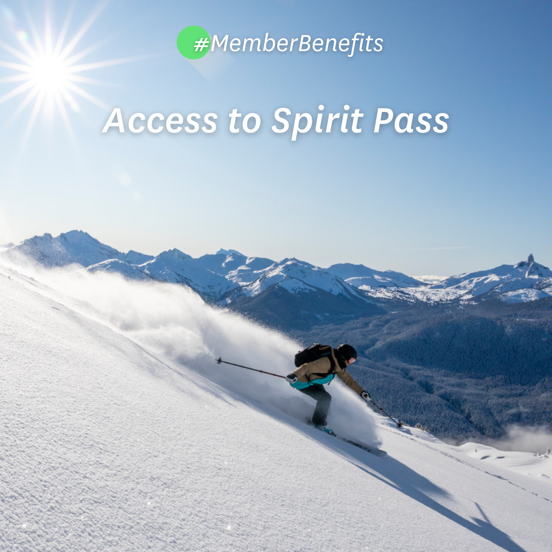 Skier riding down mountain on a sunny day blue skies and fresh powder kicking up behind