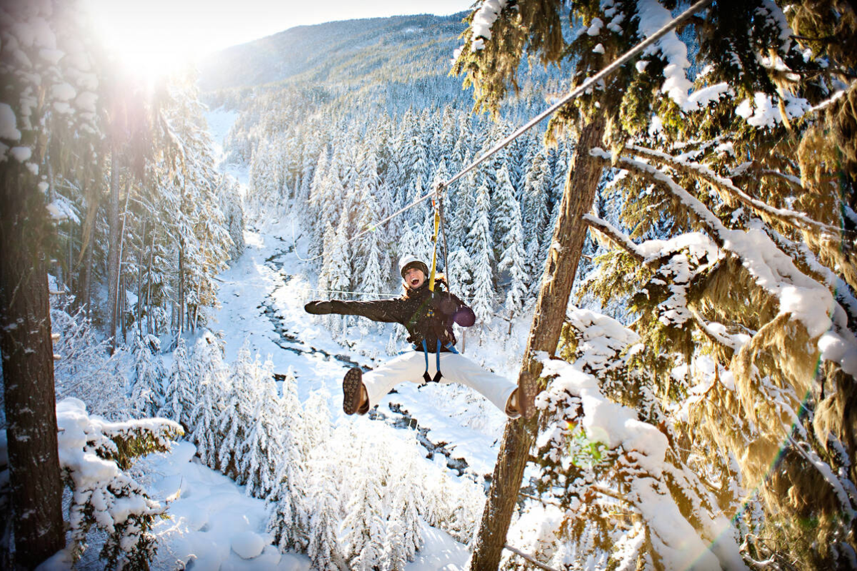 Skier riding down mountain on a sunny day blue skies and fresh powder kicking up behind