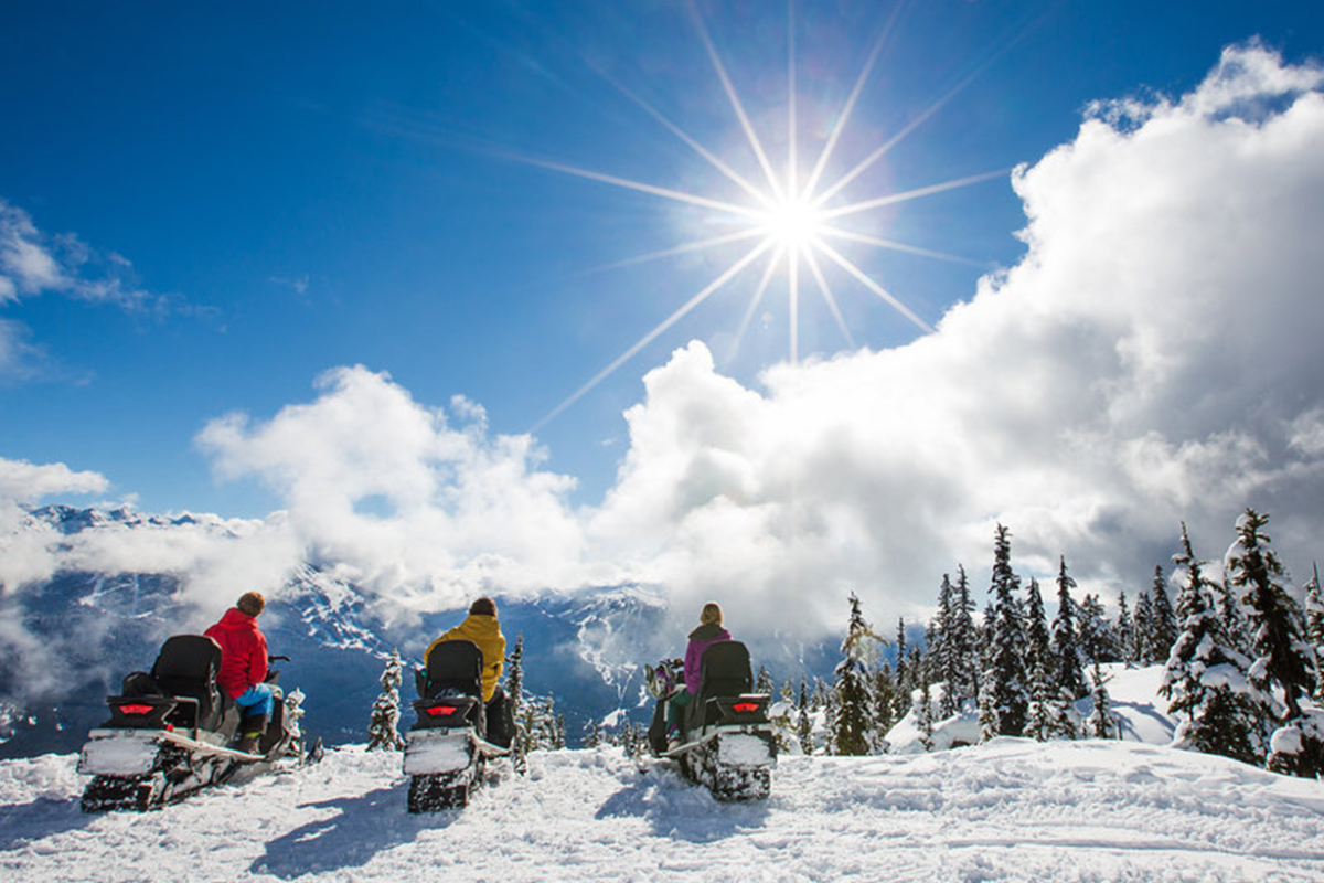 Skier riding down mountain on a sunny day blue skies and fresh powder kicking up behind