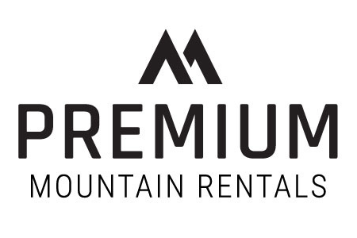 Skier riding down mountain on a sunny day blue skies and fresh powder kicking up behind