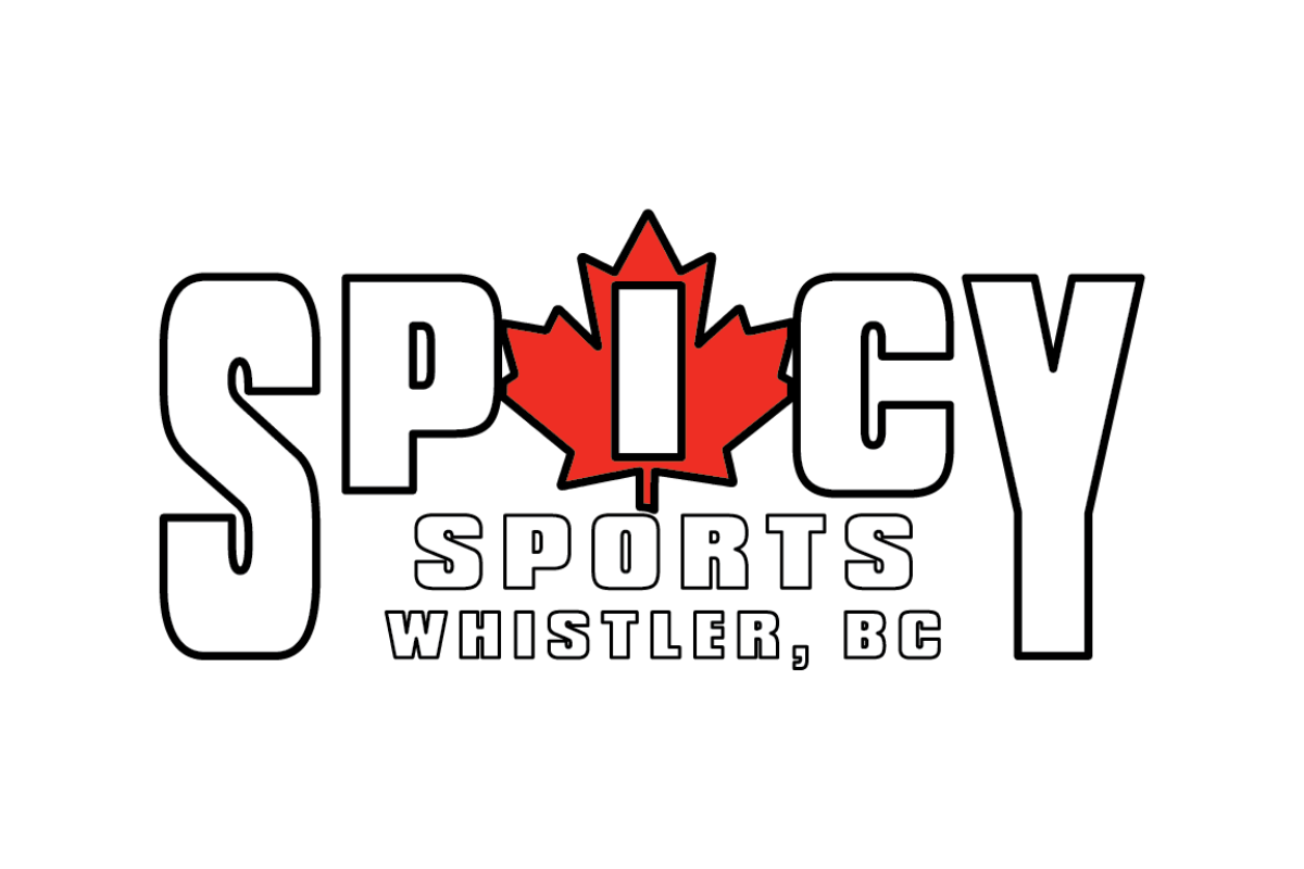 Skier riding down mountain on a sunny day blue skies and fresh powder kicking up behind