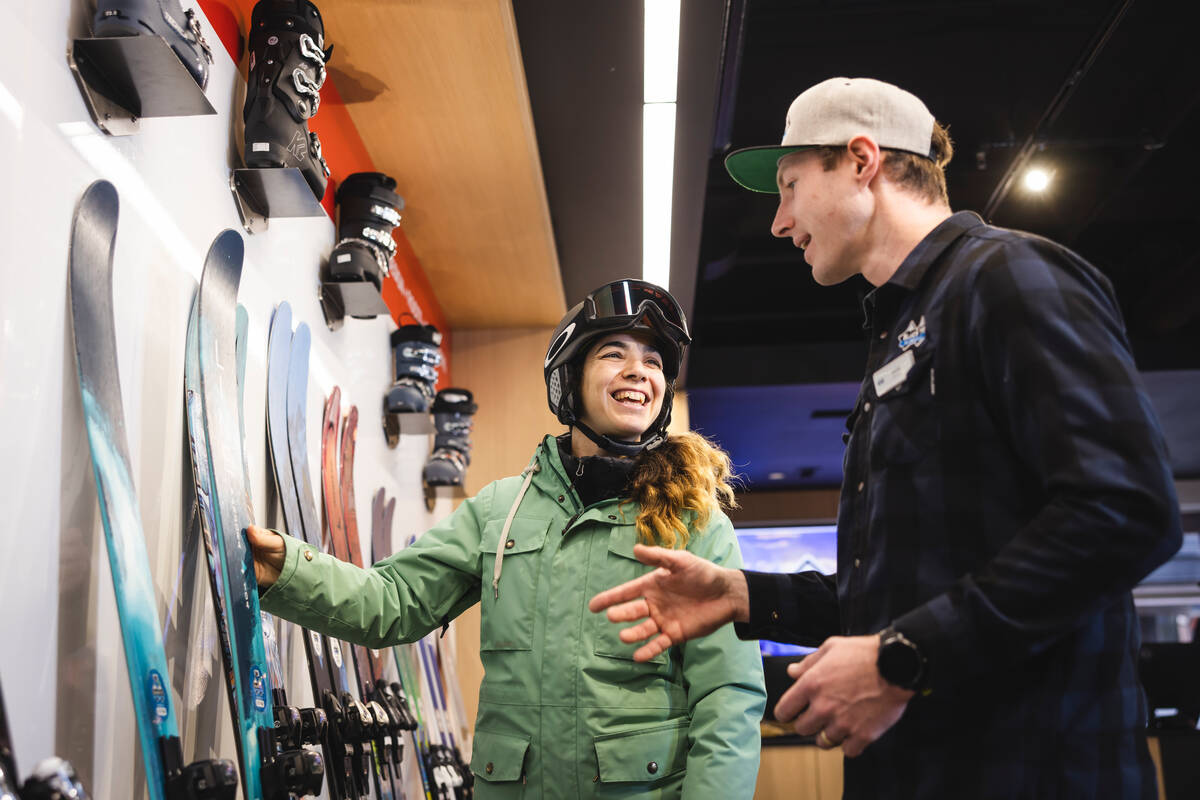 Skier riding down mountain on a sunny day blue skies and fresh powder kicking up behind